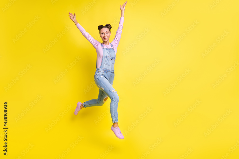Photo of funky sportive lady jump run raise hands wear jeans overall sneakers isolated yellow background