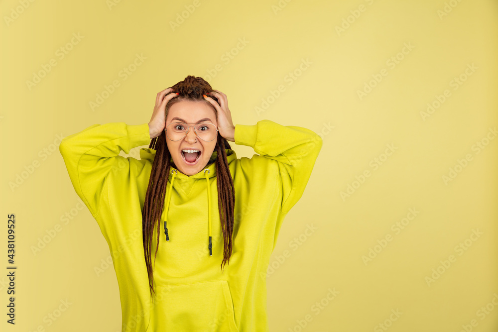 Wow. Beautiful female half-length front portrait isolated on yellow studio backgroud. Young emotional surprised woman standing with open mouth. Human emotions, facial expression concept. Wow. Beautiful female half-length front portrait isolated on yellow studio backgroud. Young emotional surprised woman standing with open mouth. Human emotions, facial expression concept.