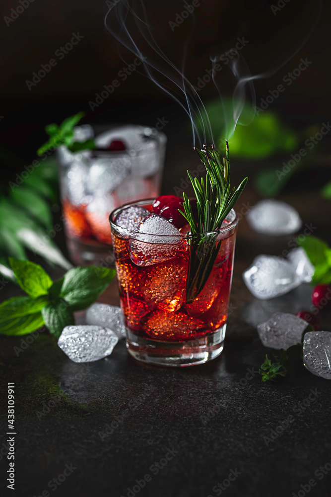 Berry alcoholic cocktail liqueur, vodka, ice and rosemary. Refreshing cool drink, berry liqueur or red alcoholic cocktail. - obrazy, fototapety, plakaty 
