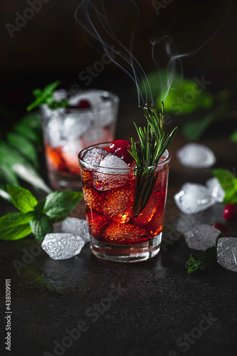 Berry alcoholic cocktail liqueur, vodka, ice and rosemary. Refreshing cool drink, berry liqueur or red alcoholic cocktail.