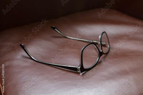 Detail of eyeglasses on top of a leather chair