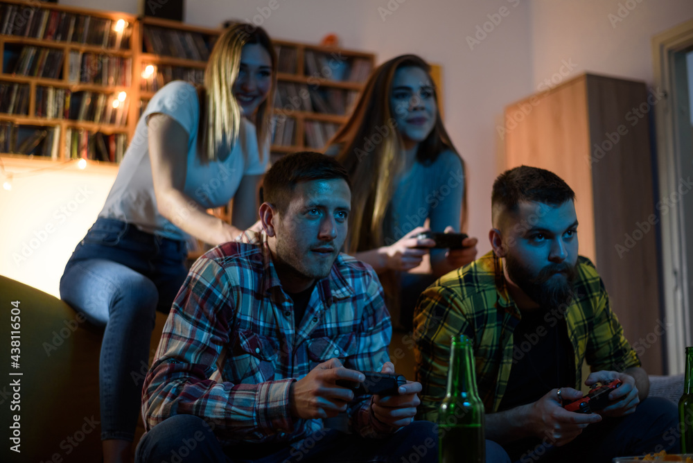 A group of friends playing video games while relaxing at home A group of friends playing video games while relaxing at home