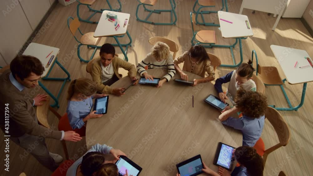 Male teacher helping students with tablet computers at lesson.