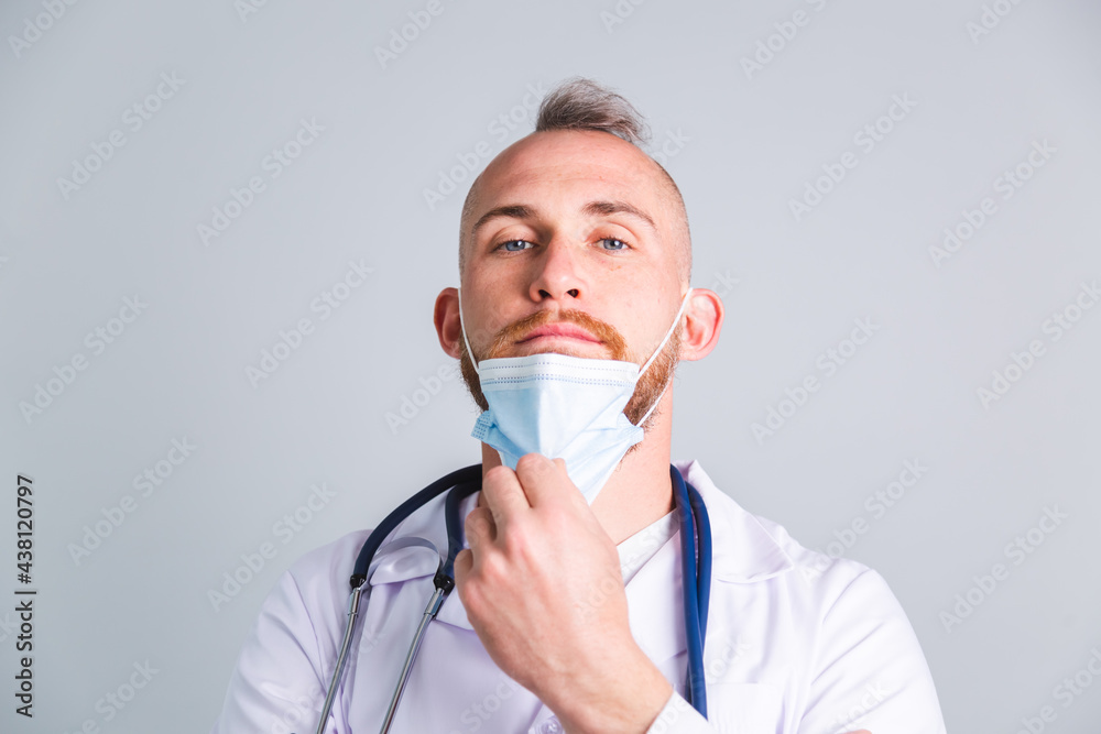 Handsome male doctor on gray background with takes off protective medical mask Handsome male doctor on gray background with takes off protective medical mask