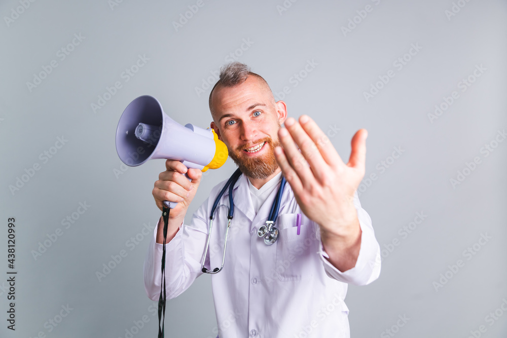 Handsome male doctor on gray background shouting in megaphone ask for attention, calling everyone for vaccine Handsome male doctor on gray background shouting in megaphone ask for attention, calling everyone for vaccine