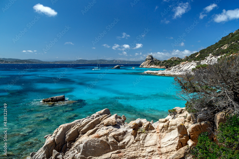 Obraz premium Scenic rocky coast in Sardinia, rock formation in the foreground and yachts in the horizon, sea with azure crystal clear water. Sardinia, Italy.
