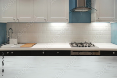 Blurred elegant marble tabletop with modern kitchen in the home background.
