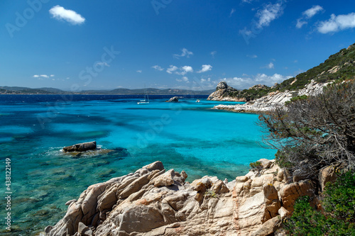 Scenic rocky coast in Sardinia, rock formation in the foreground and yachts in the horizon, sea with azure crystal clear water. Sardinia, Italy.