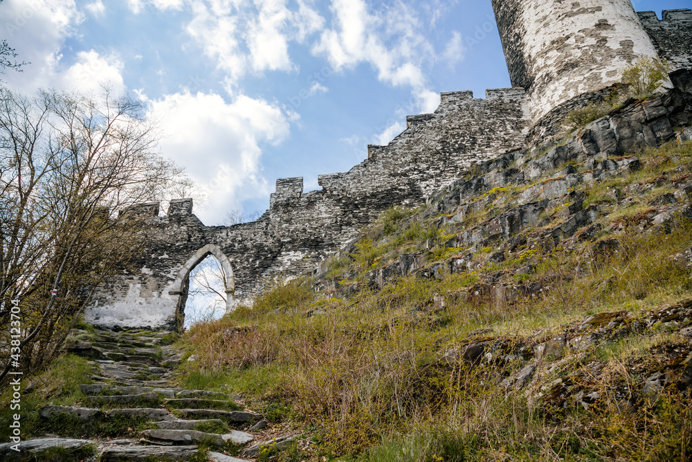 Road to medieval gothic castle Bezdez, grey stone ruin on hill at sunny day, ancient fortress walls, fairytale stronghold, scalloped walls, entrance gate, North Bohemia, Czech Republic