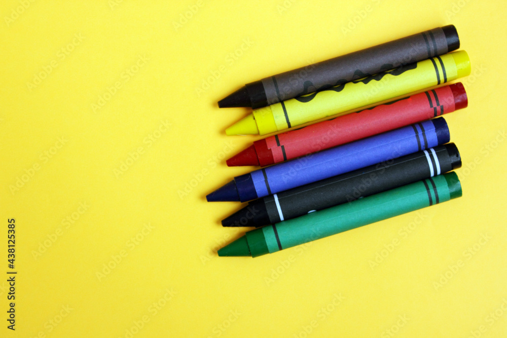 Fototapeta premium Colored pencils on a yellow background. Lots of different colored wax pencils. Colored pencil. Drawing lessons, hobbies, education, creativity. Close-up. Copy space. Background. Flat lay.