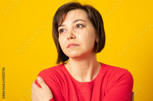 Sad young woman wearing casual sweater over yellow background, hugging oneself sad and pensive, smiling confident. Self love and self care.
