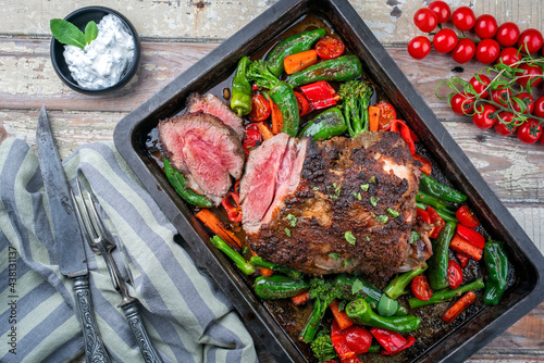Traditional Greek barbecue lamb roast with vegetable and tzatziki offered as top view in a rustic metal tray