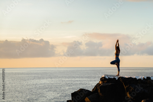 Faceless woman performing Tree with Arms Up pose against sea photo