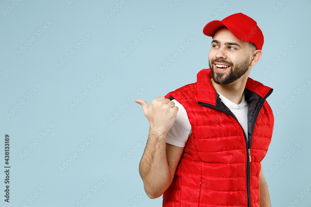 Delivery guy employee man in red cap white T-shirt uniform workwear work as dealer courier recommend suggest select promo area advert isolated on pastel blue color background studio. Service concept. Delivery guy employee man in red cap white T-shirt uniform workwear work as dealer courier recommend suggest select promo area advert isolated on pastel blue color background studio. Service concept.