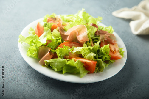 Healthy green salad with tomato and prosciutto