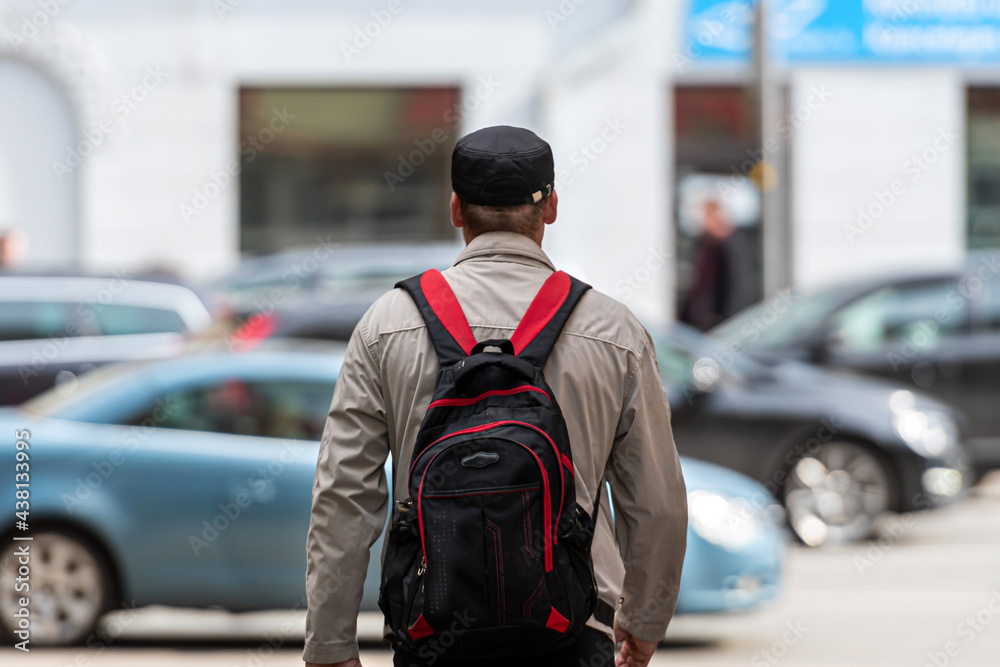 rear view of a man with a backpack on a defocused street background, closeup