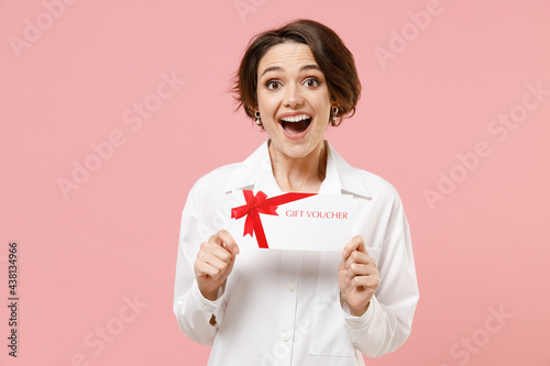 Young fun surprised amazed employee business secretary woman corporate lawyer in classic formal white shirt work in office hold gift voucher flyer mock up isolated on pastel pink background studio