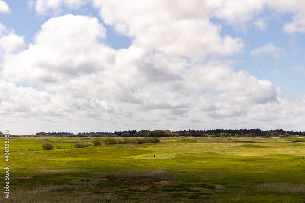 a shot of a blue sky with white cumulus clouds in the sky and in the foreground is a green large meadow. clouds cast a shadow on the grass. a shot of a blue sky with white cumulus clouds in the sky and in the foreground is a green large meadow. clouds cast a shadow on the grass.