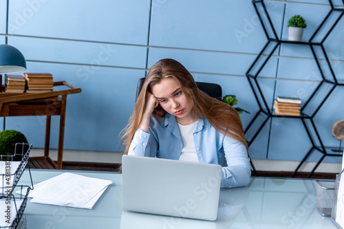 Tired owerworked blonde woman at the office with computer photo