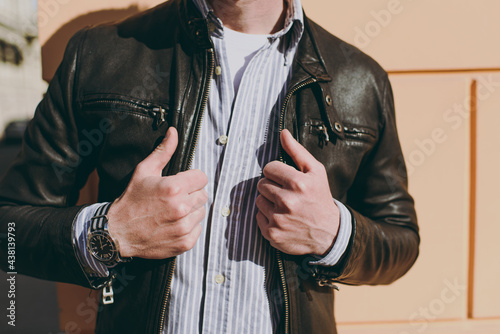 Close up cropped photo portrait shot young stylih trendy fashionable caucasian man 20s in black leather jacket shirt stand near building wall outdoors Concept of people urban lifestyle and clothes