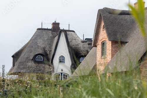 a Sylt typical brick house with a thatched roof. shot of special red houses with meadow and grass in the foreground.  photo