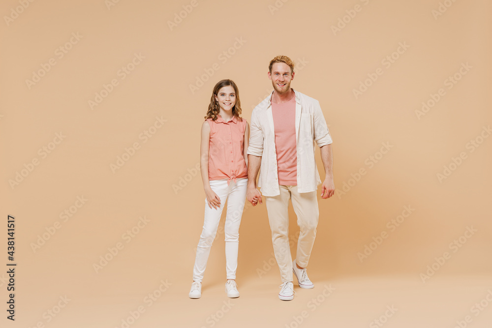 Full length cool young parent man have fun with cute child teen girl in casual pastel clothes. Daddy little kid daughter stand hold hands isolated on beige background Father's Day Love family concept Full length cool young parent man have fun with cute child teen girl in casual pastel clothes. Daddy little kid daughter stand hold hands isolated on beige background Father's Day Love family concept