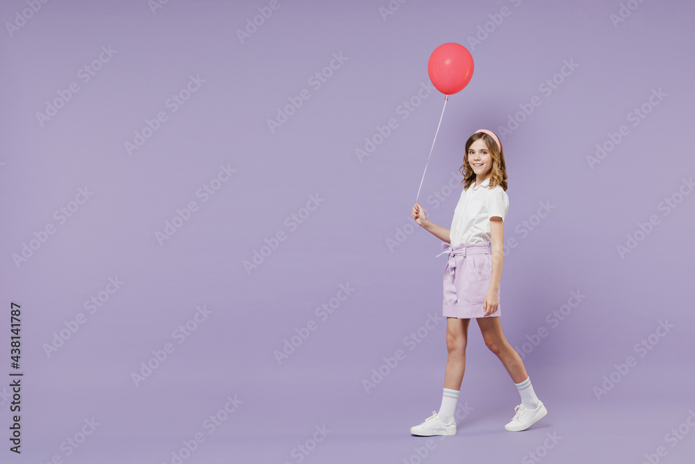 Full length side view little kid girl 12-13 year old in white shirt celebrate birthday holiday party hold air inflated helium balloon isolated on purple background Children childhood lifestyle concept Full length side view little kid girl 12-13 year old in white shirt celebrate birthday holiday party hold air inflated helium balloon isolated on purple background Children childhood lifestyle concept