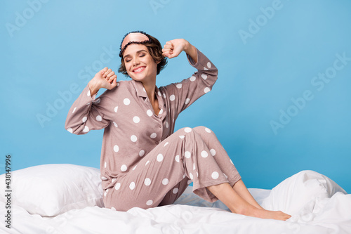 Full length photo of young cheerful girl happy positive smile sit bed awake morning isolated over blue color background