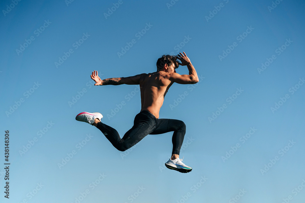 Fast runner jumping during workout under blue sky Fast runner jumping during workout under blue sky