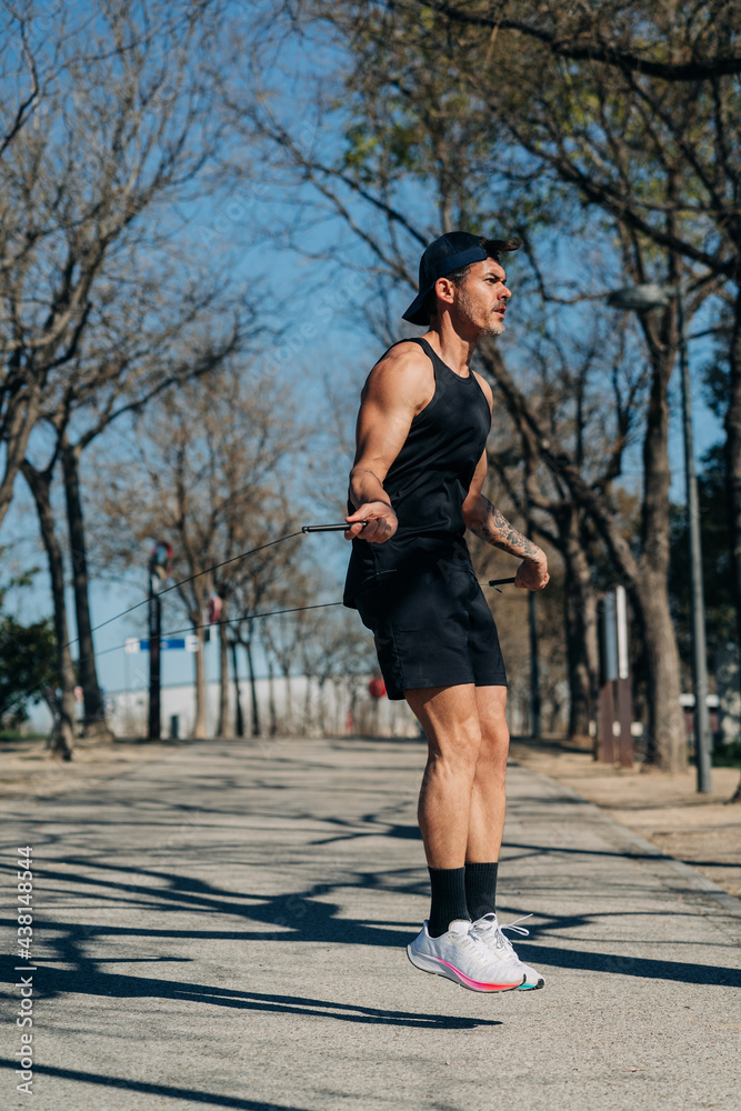Active sportsman with jumping rope working out on pavement Active sportsman with jumping rope working out on pavement