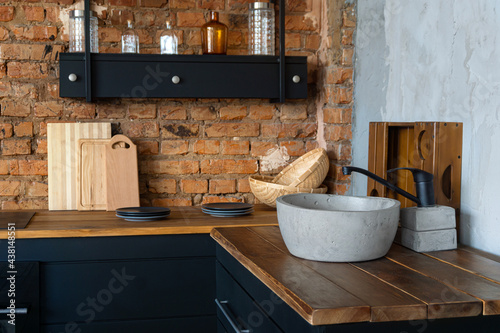 Open space industrial loft kitchen with vintage decor, black cabinets and concrete basin sink
