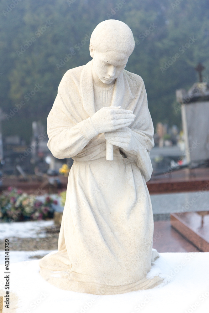 Valenciennes, France, 2017/01/02. Statue of a young girl with a candle on a tombstone at Saint Roch cemetery.