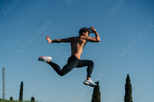 Fast runner jumping during workout under blue sky photo