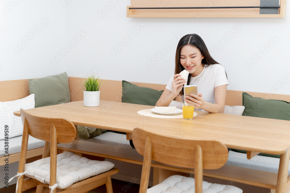 Happy asian woman using mobile phone during breakfast or eating lunch while working from home. Happy asian woman using mobile phone during breakfast or eating lunch while working from home.