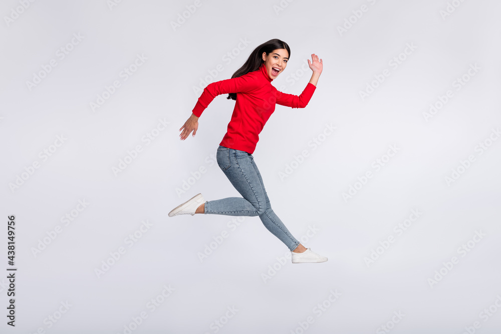 Full size profile side photo of happy excited good mood asian girl running fast in air isolated on grey color background Full size profile side photo of happy excited good mood asian girl running fast in air isolated on grey color background