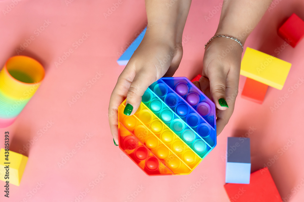 female hand playing with rainbow toy antistress pop it female hand playing with rainbow toy antistress pop it