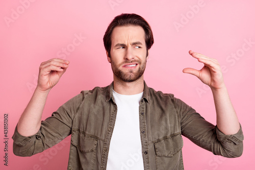 Portrait of attractive irritated guy playing with hands like talking isolated over pink pastel color background