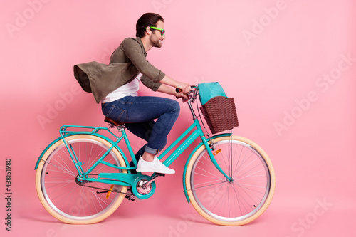 Fototapeta Naklejka Na Ścianę i Meble -  Full length body size profile side view of attractive cheerful guy riding bike isolated over pink pastel color background