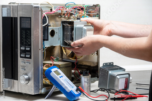 Repair of the microwave oven. A woman replaces a magnetron. photo