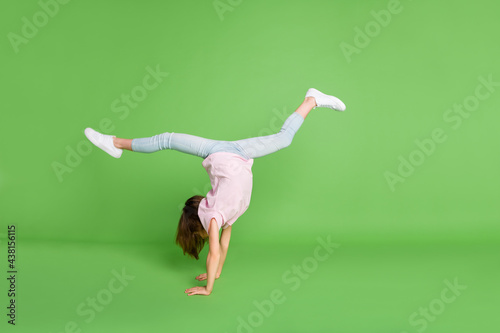 Fototapeta Naklejka Na Ścianę i Meble -  Full length profile side photo of young girl stand on hands gymnastics sport isolated over green color background