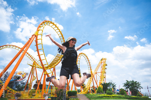 Fotografiet a women has fun happy joy day at amusement park in summer sunny day, roller coaster, jumping girl, vacation leisure holiday, activities concept