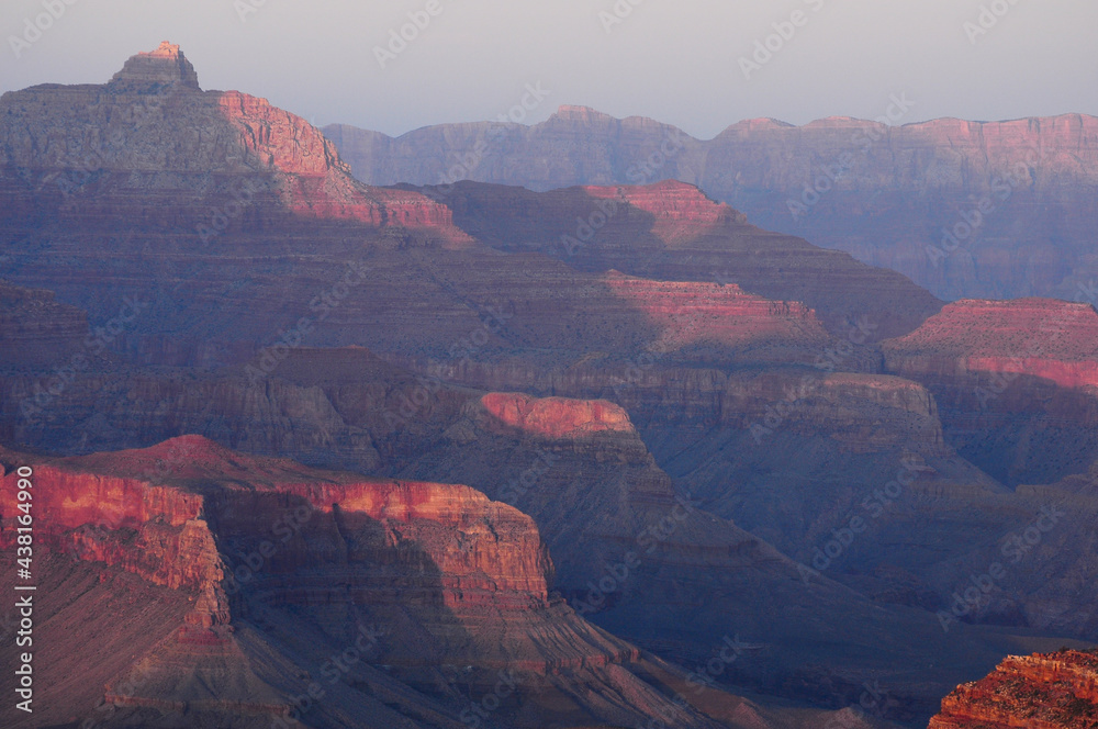 The day ends as the sun accentuates the shapes and saturates the reddish colors of the South Rim Mountains in Grand Canyon National Park, Arizona.