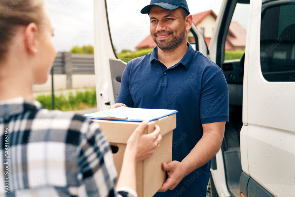 Fototapeta premium Smiling delivery person giving package to woman