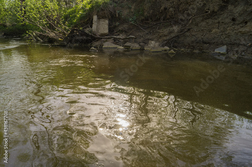Photo of a small river (stream) polluted with broken concrete slabs.