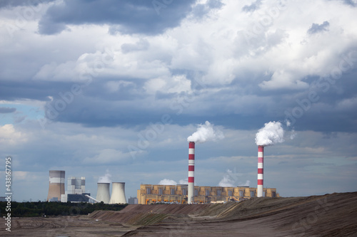 A view of a lignite-fired power plant against the background of an opencast coal mine. Photo taken in daylight. Lots of little clouds in the sky
