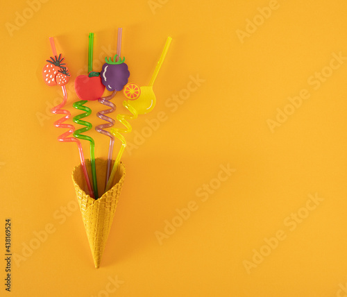 yellow ice cream cone with colorful tubes on the yellow illuminating summer sunny backround with copy space. minimal flat lay. abstract art.