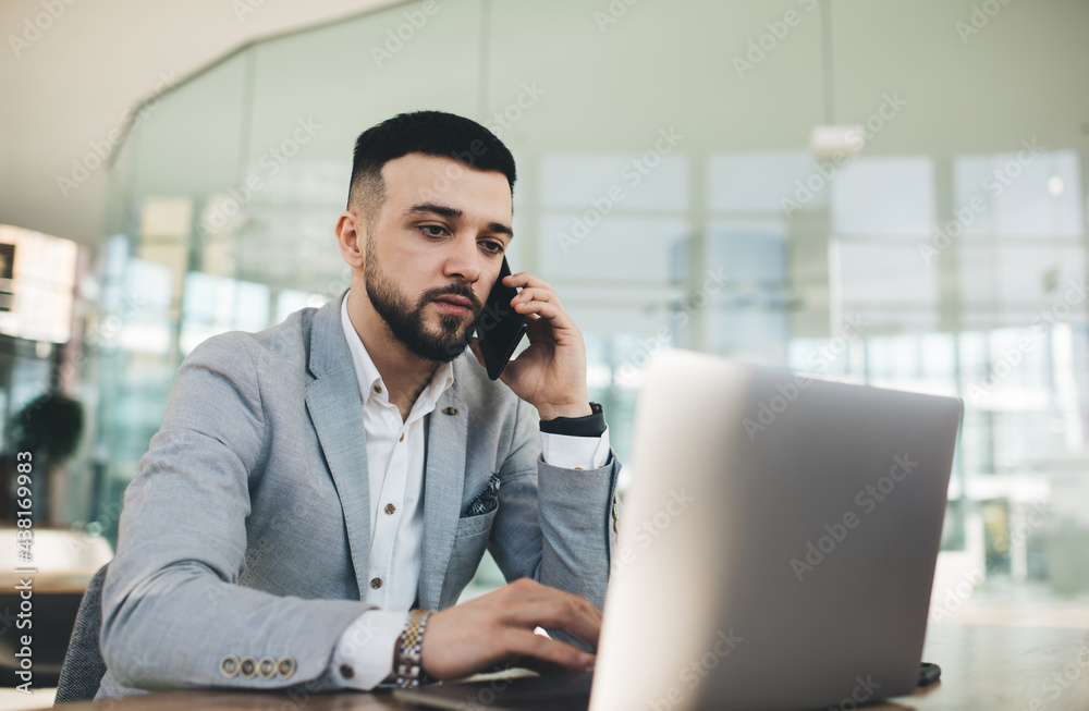 Focused businessman having conversation on smartphone and using laptop Focused businessman having conversation on smartphone and using laptop