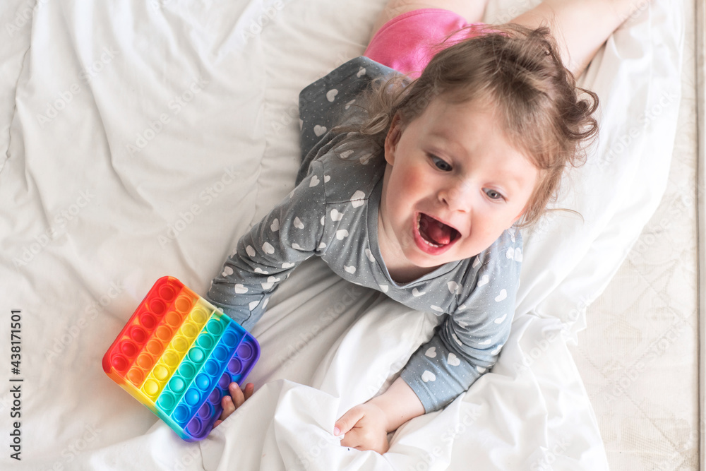 Naklejka premium a small child is playing a modern anti-stress pop it toy. baby plays rubber educational toy at home
