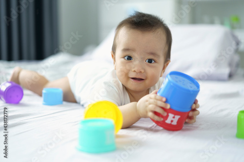 Asian baby boy playing a tower cup toy on a bed in bedroom. A kid playing and smile. kid development and creativity concept