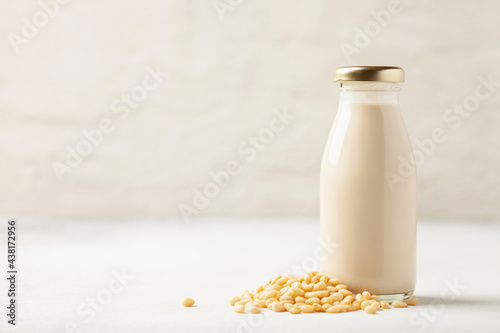 Pine milk in a bottle and pine nuts on the table. Dairy free alternative product